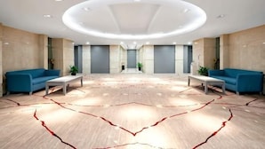 A spacious lobby with a modern design, featuring a central seating area with sofas and a patterned carpet. - Sports International Hotel (Kunshan)