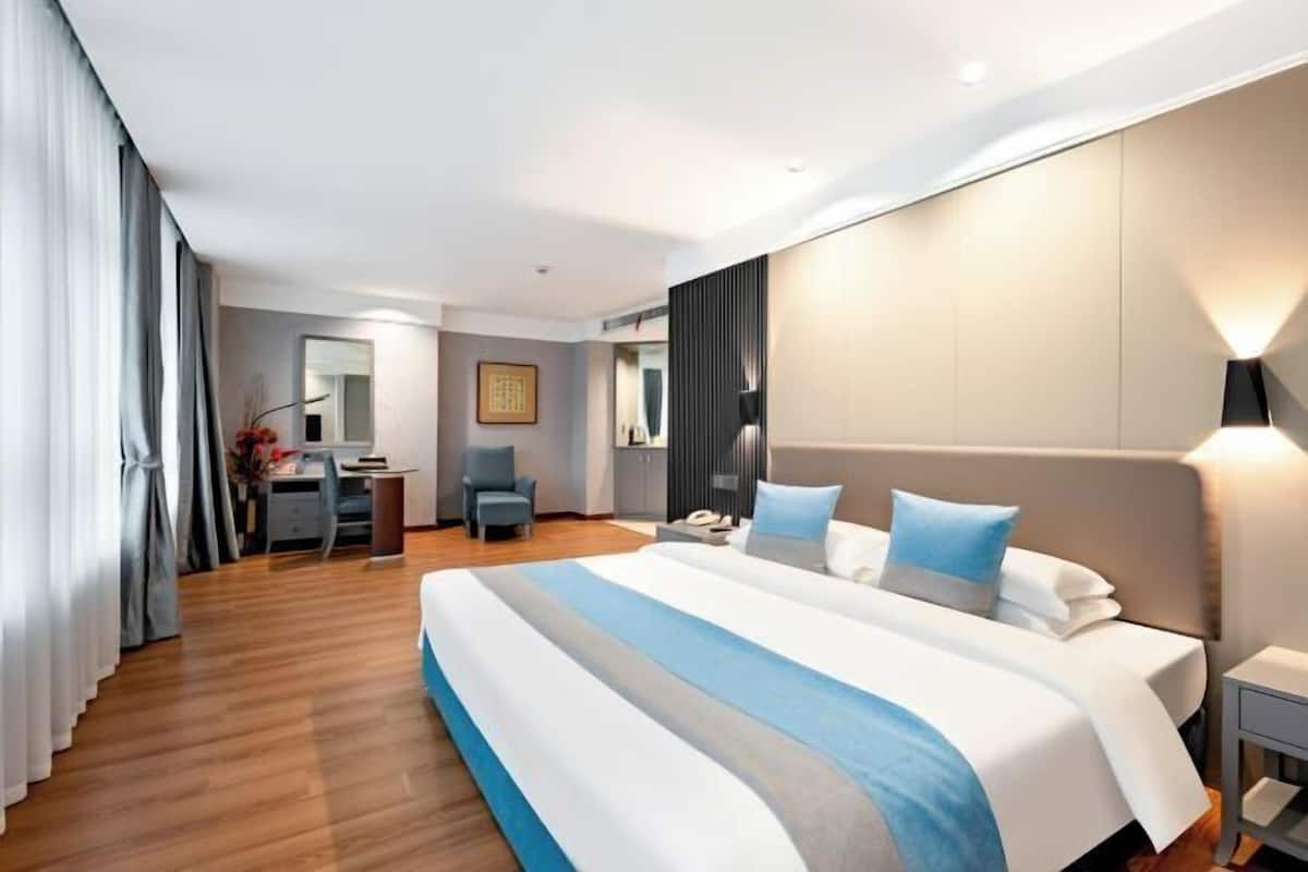 A modern hotel room with a large bed, a desk, and a chair.