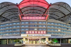 A large hotel with a distinctive red and white facade, multiple floors, and a prominent entrance. - Sports International Hotel (Kunshan)