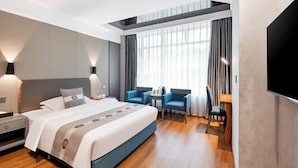 A modern hotel room with a large bed, a desk, two chairs, a TV, and a window with curtains. - Sports International Hotel (Kunshan)