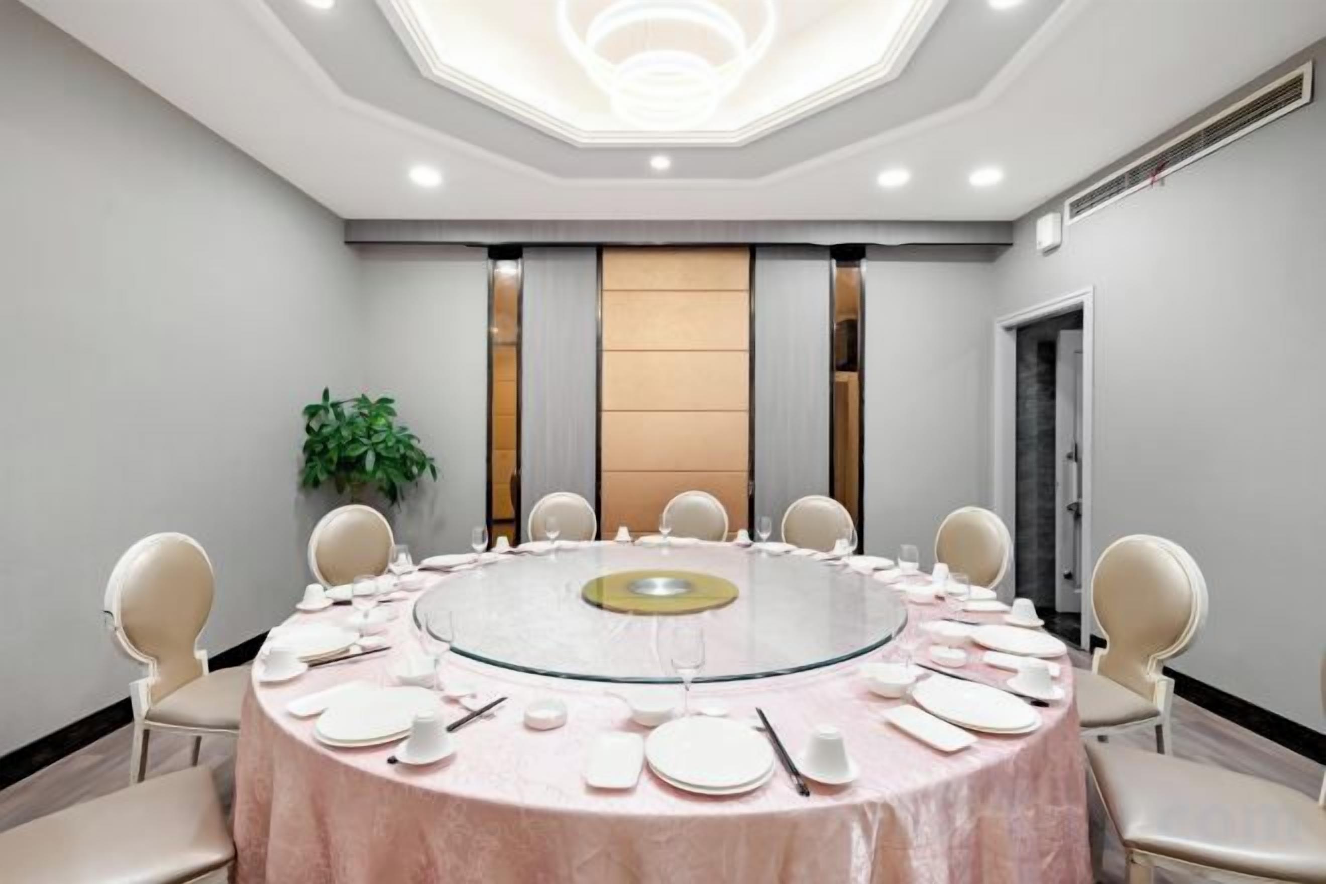 A conference room with a round table, chairs, and a glass partition.