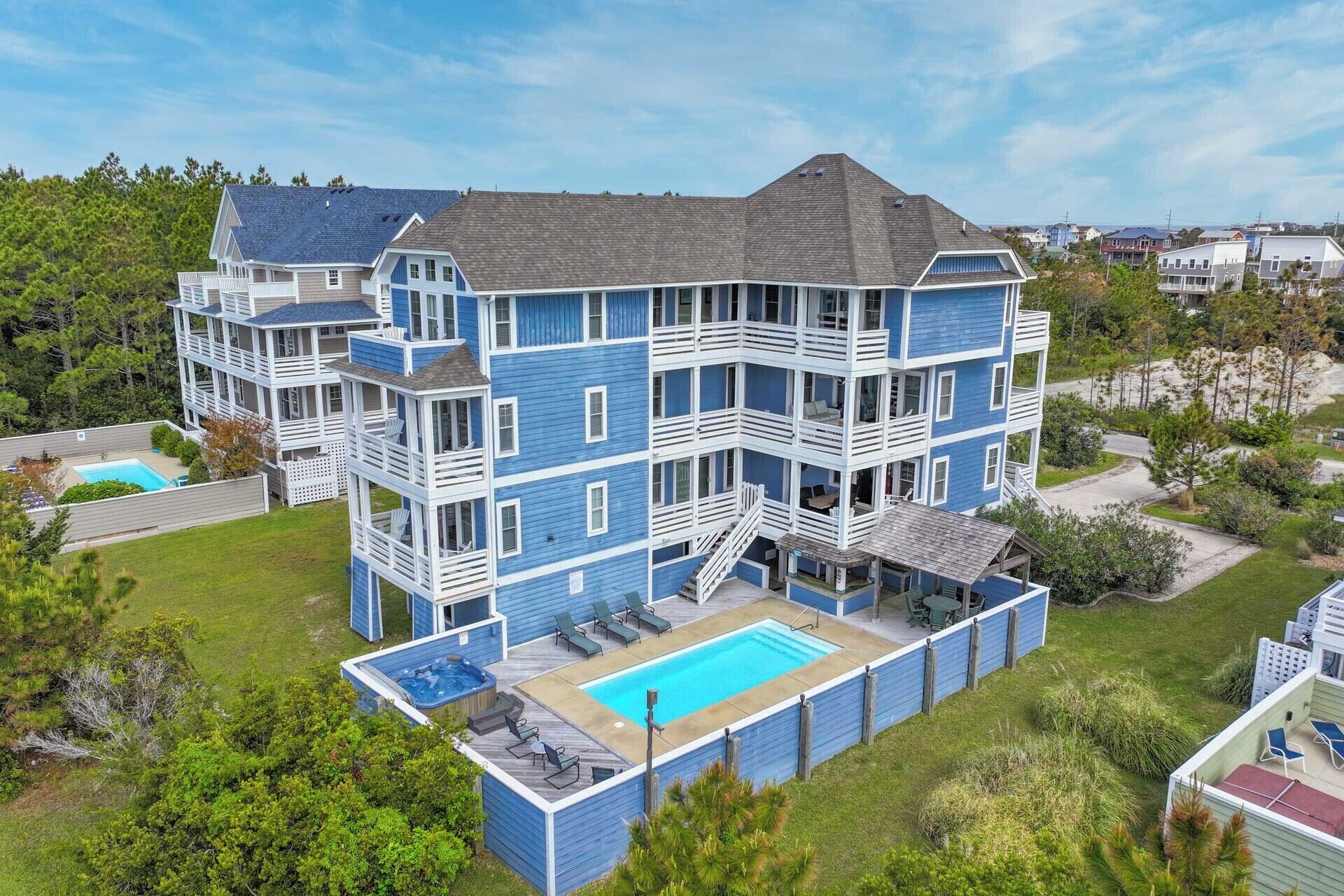 A multi-story building with a pool, outdoor seating, and a staircase leading to the upper levels.
