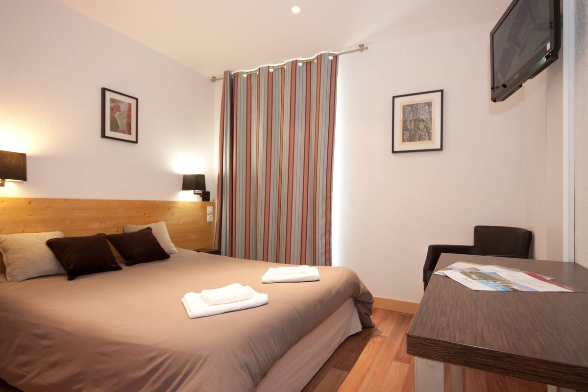Une chambre d’hôtel avec un lit, un bureau et une télévision.