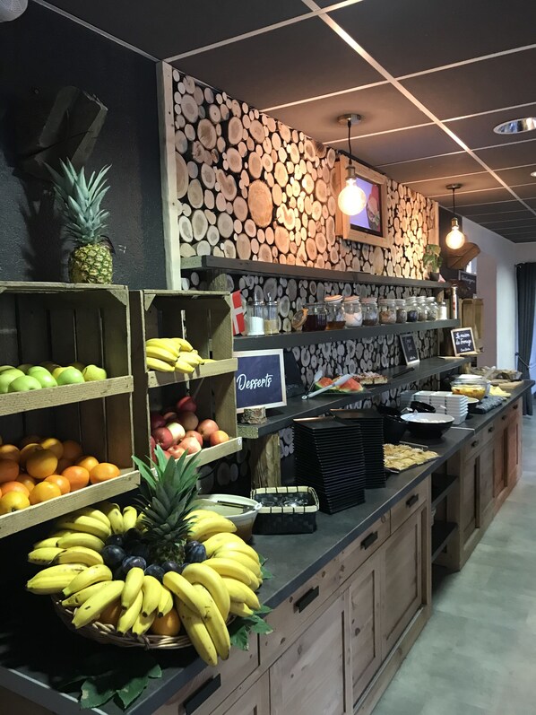 A buffet area with various fruits and desserts displayed on shelves and counters.