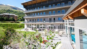A modern hotel with a pool area, outdoor seating, and a view of the surrounding landscape. - Village vacances Neaclub - La Pulka (Valloire)