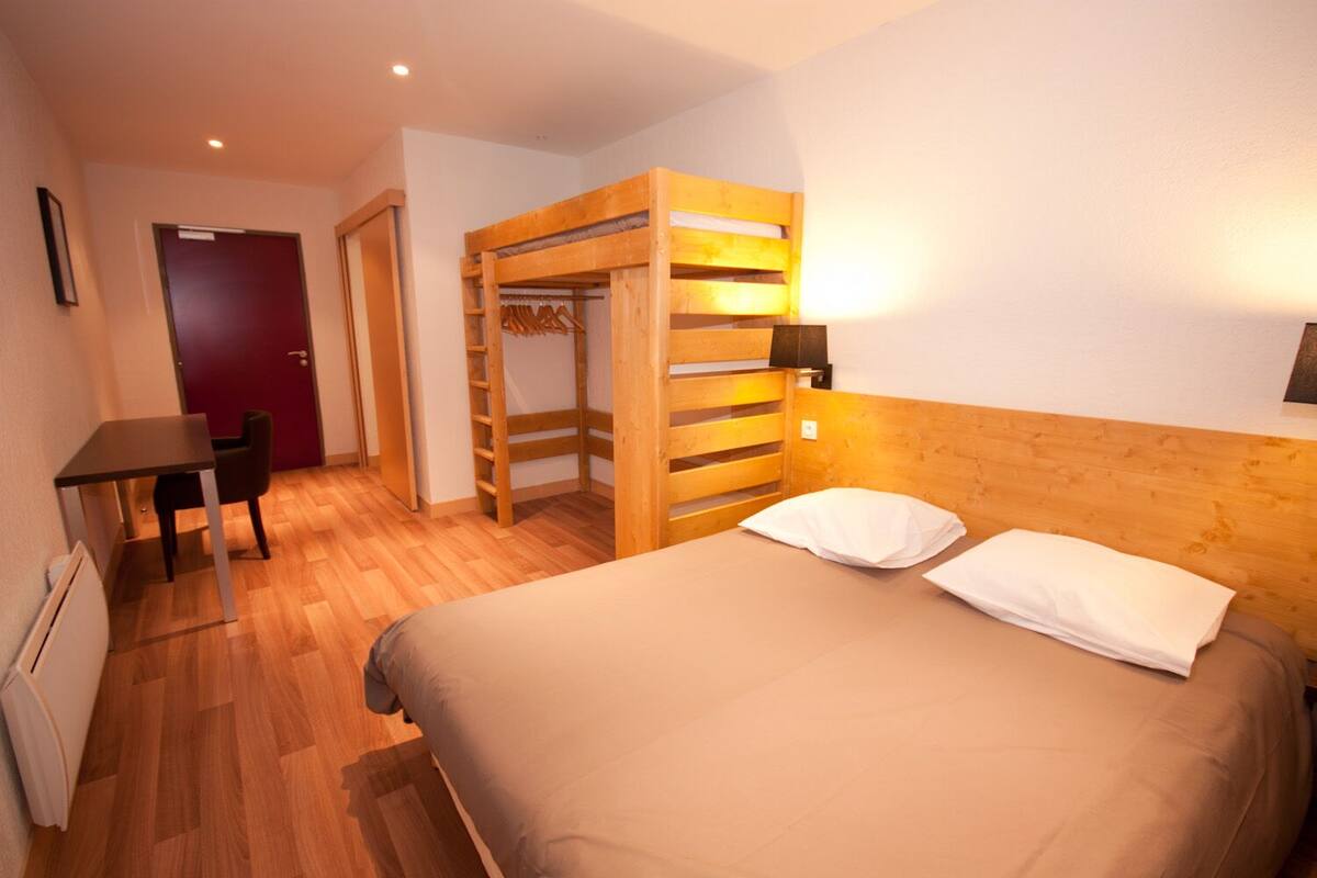 Une chambre d’hôtel avec un lit, un bureau et une armoire en bois.