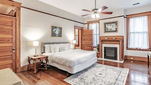 Une chambre à coucher avec un lit, une table de chevet, un ventilateur de plafond, une cheminée et des murs en bois.