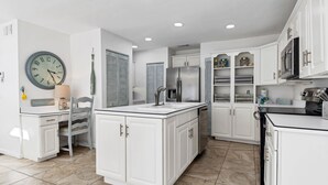 A modern kitchen with white cabinetry, a central island, and a built-in refrigerator. - 2-Min Walk to Holmes Beach - Walk to Shops & Dining - Quiet Tropical Townhouse (Holmes Beach)