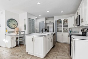 A modern kitchen with white cabinetry, a central island, and a built-in refrigerator.
