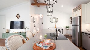 A modern kitchen with a central island, stainless steel appliances, and a dining area with wicker chairs. - Boho-Chic South CLT Oasis ★ Custom Home ★ Sleeps 6 (Charlotte)