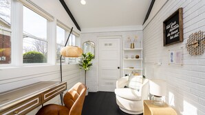 A room with a desk, two chairs, a lamp, a mirror, and a shelf with decorative items. - Boho-Chic South CLT Oasis ★ Custom Home ★ Sleeps 6 (Charlotte)