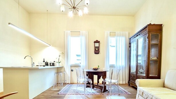 A spacious living area with a dining table, chairs, a sofa, and a wooden cabinet. - LUXURY UFFIZI - Three Bedroom Apartment, Sleeps 12 (Florence)