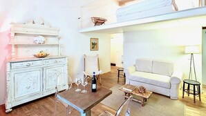 A spacious living area with a white sofa, a dining table with wine glasses, a white cabinet, and a chandelier. - LUXURY UFFIZI - Three Bedroom Apartment, Sleeps 12 (Florence)
