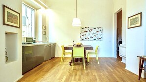 A compact kitchen with a dining area, wooden flooring, and a hanging light fixture. - LUXURY UFFIZI - Three Bedroom Apartment, Sleeps 12 (Florence)
