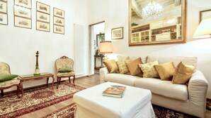 Un salon comprenant un canapé, des fauteuils, une table basse, un tapis à motifs et des tableaux encadrés accrochés au mur.