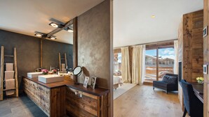 Un baño moderno con tocador de madera, un espejo grande y vistas a un dormitorio con cama y cortinas.
