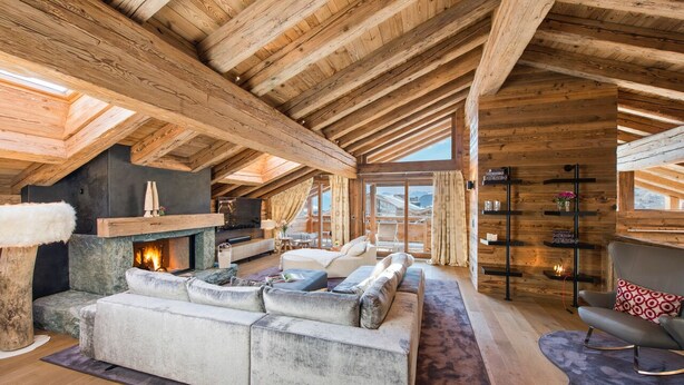 Un loft espacioso con vigas de madera a la vista, chimenea, un sofá seccional grande y una zona de estar acogedora.