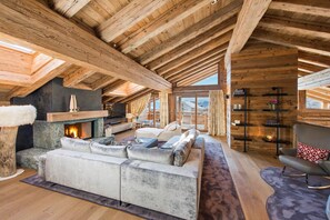 Un loft spacieux avec des poutres apparentes, une cheminée, un grand canapé d’angle et un coin salon confortable.