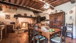 Un comedor rústico con mesa y sillas de madera, chimenea y pared de piedra.