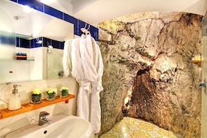 Une salle de bain avec un mur en pierre, une baignoire, un lavabo et un miroir.