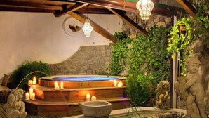 A hot tub area with stone walls, candles, and stone sculptures.