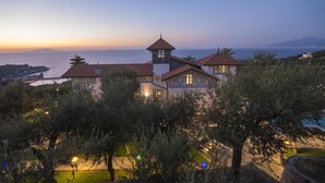 Une villa côtière dotée d’une tour imposante, de toits en terrasses et offrant une vue sur la mer.