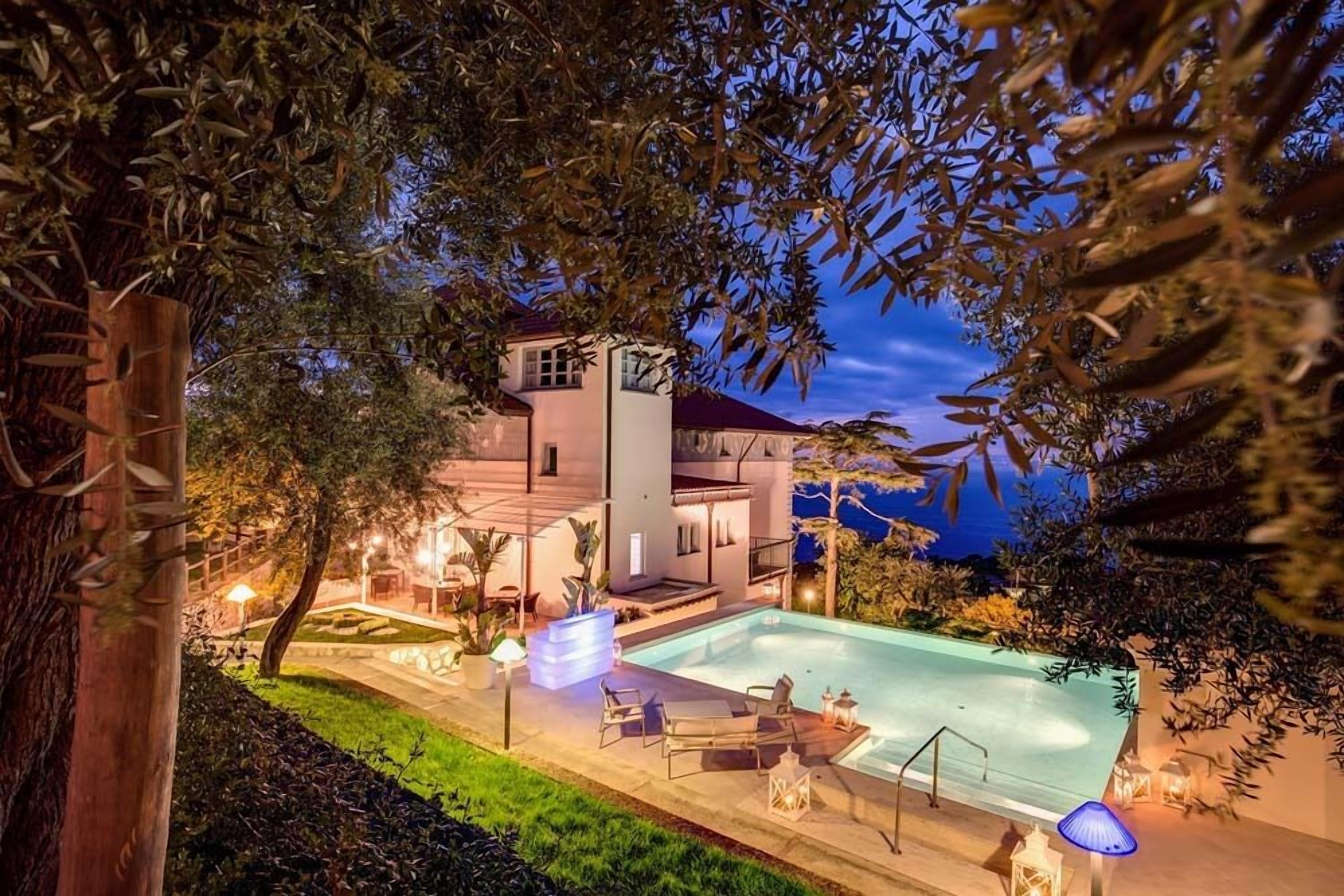 Une maison moderne dotée d’une piscine, d’un espace salon extérieur et d’une terrasse bien éclairée.