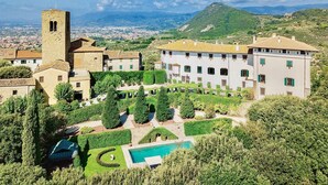 Une vaste villa dotée d’une piscine, entourée de jardins luxuriants et agrémentée d’une tour.