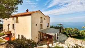 A two-story house with a tiled roof, a stone-paved entrance, and a view of the sea. - VILLA MARATEA - Six Bedroom Villa, Sleeps 12 (Maratea)