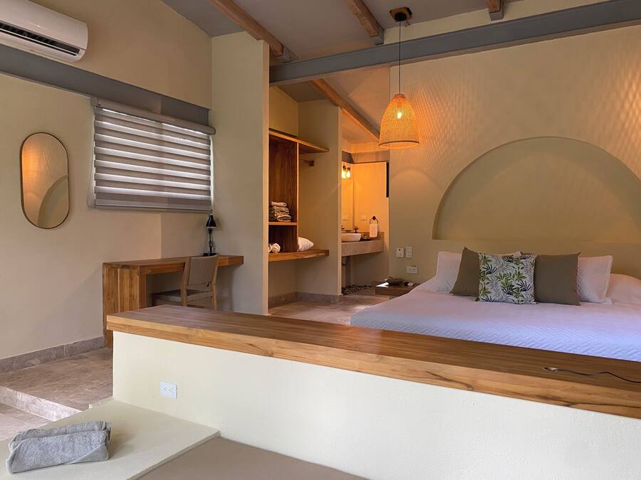 Ein Schlafzimmer mit Bett, Nachttisch, Lampe und einer hölzernen Bank.
