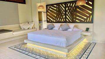 Un dormitorio moderno con una cama grande, un sofá, un panel decorativo en la pared y una lámpara colgante.