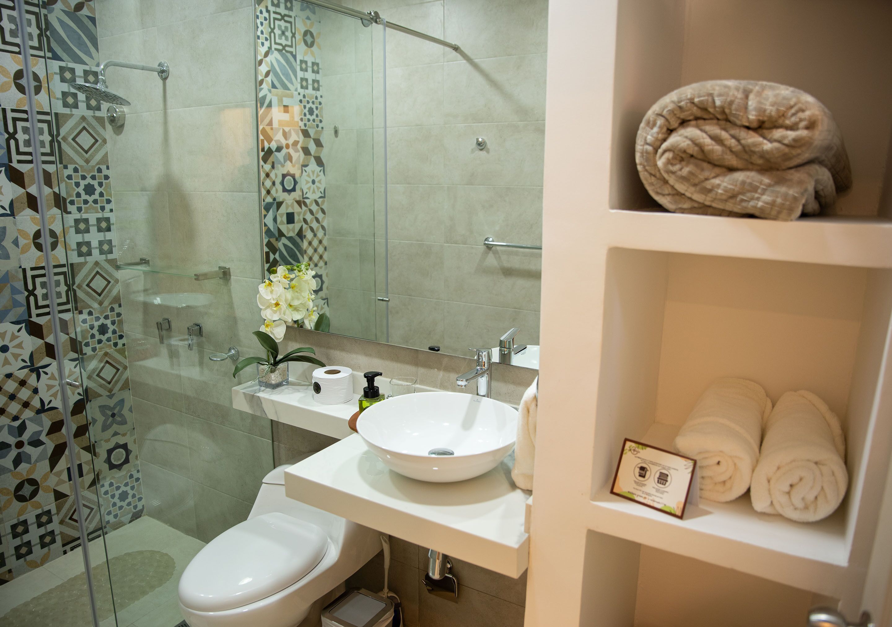 A bathroom with a glass shower enclosure, a white sink, a toilet, and a towel rack.