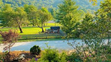A rural landscape with a house, a fenced field, and a body of water.
