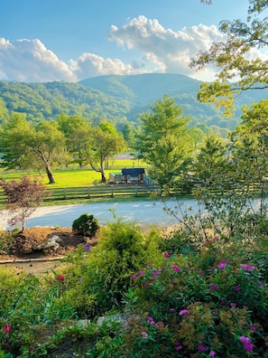 A rural landscape with a house, a fenced field, and a body of water.