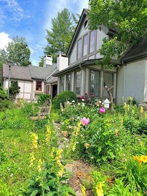 A traditional house with a garden, a stone pathway, and a white fence.