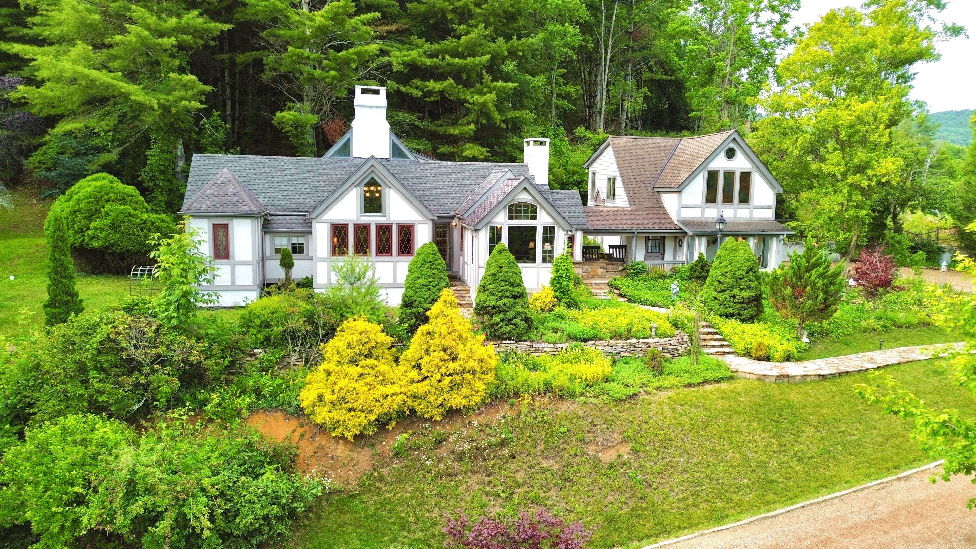 Une grande maison à deux étages, dotée d’un jardin bien entretenu et d’un chemin de pierre menant à l’entrée.