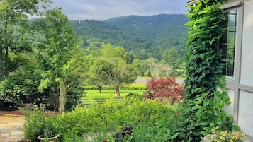 Un jardin avec un sentier de pierres menant à une maison qui offre une vue sur une vallée verdoyante.