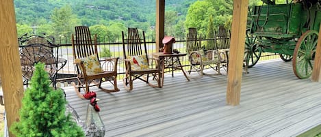 A covered deck with rocking chairs, a small Christmas tree, and a green carriage.