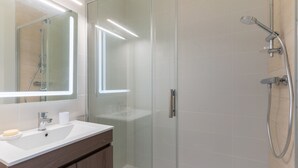 Une salle de bain moderne avec une douche à parois de verre, un lavabo blanc et un miroir au-dessus.