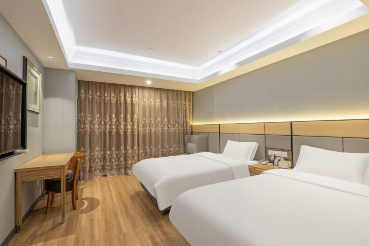 Quarto de hotel com duas camas, uma escrivaninha e uma cadeira.