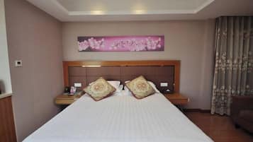 A hotel room with a large bed, two bedside tables, a nightstand, a headboard, and a wall-mounted artwork.