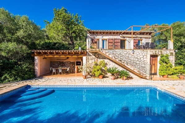 Relax in a Mediterranean-style villa with a spacious outdoor area featuring a swimming pool, stone staircase, and lush greenery.