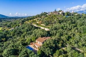 Surrounded by lush greenery, this villa offers expansive views of the surrounding landscape and distant hills.