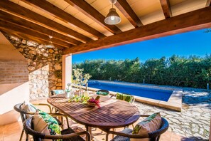 Relax by the pool in a serene outdoor patio area with a clear view, featuring a table and wicker chairs.