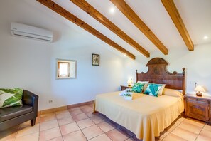 Cozy retreat with a bed, bedside tables, and a sofa, set against a wooden ceiling with exposed beams.