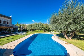Relax by the pool surrounded by lush trees and lounge chairs.