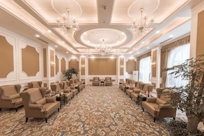 A conference room with a patterned carpet, multiple seating arrangements, and a chandelier.