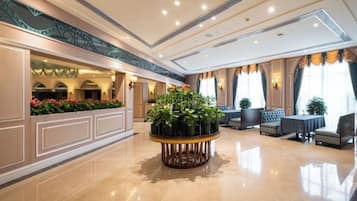 A hotel lobby with a round table, seating area, and a reception desk.