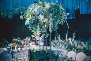 A decorated indoor setting with floral arrangements and tables set for an event.