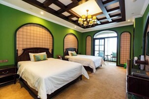 Habitación de hotel con dos camas, una araña y paredes verdes.